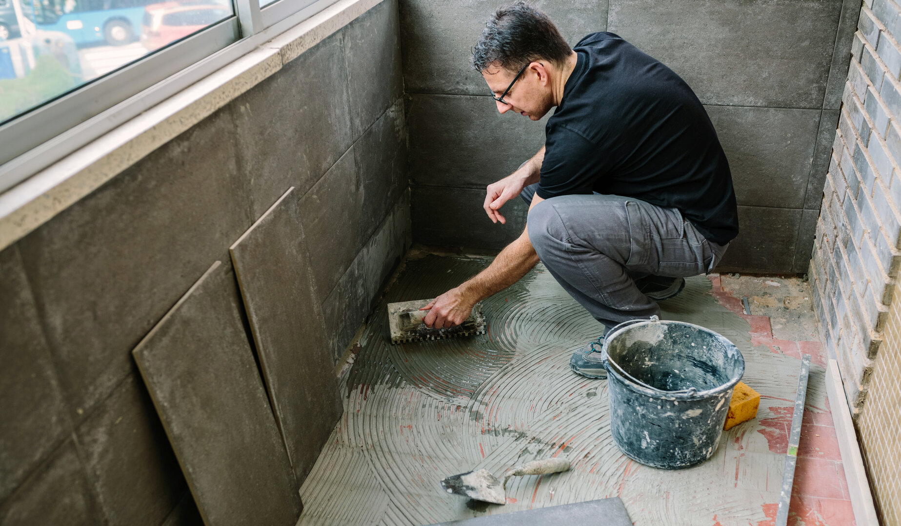 Profesional instalando baldosas durante una reforma de baño, parte del servicio de reformas integrales de DM’Martínez